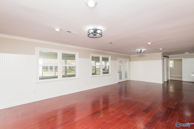spare room featuring a barn door, ornamental molding, and dark hardwood / wood-style flooring