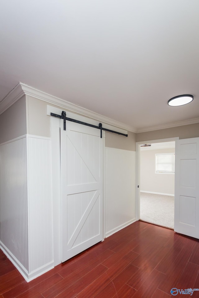 interior space with hardwood / wood-style flooring, ornamental molding, and a barn door