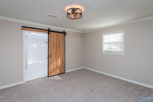 unfurnished room with crown molding, a barn door, and carpet flooring