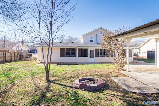 back of property featuring a sunroom, a fire pit, and a lawn