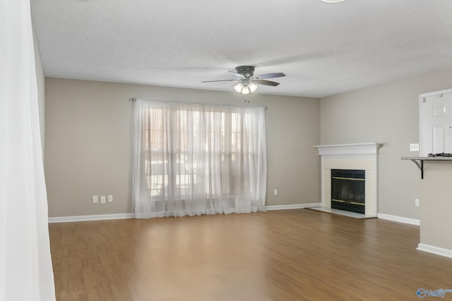 unfurnished living room featuring ceiling fan, a textured ceiling, and dark hardwood / wood-style flooring