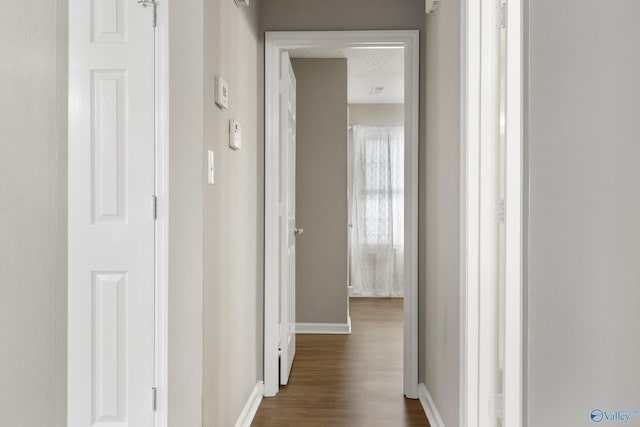 hallway with dark wood finished floors and baseboards