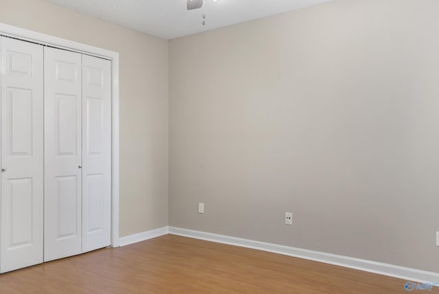 unfurnished bedroom with baseboards, a ceiling fan, wood finished floors, a textured ceiling, and a closet