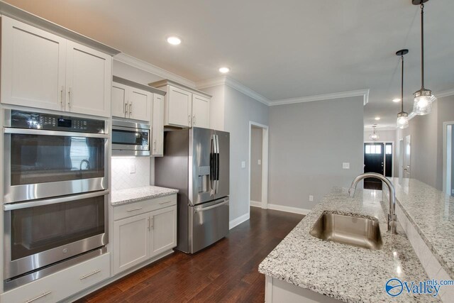 kitchen featuring backsplash, an island with sink, dark wood-type flooring, stainless steel appliances, and hanging light fixtures