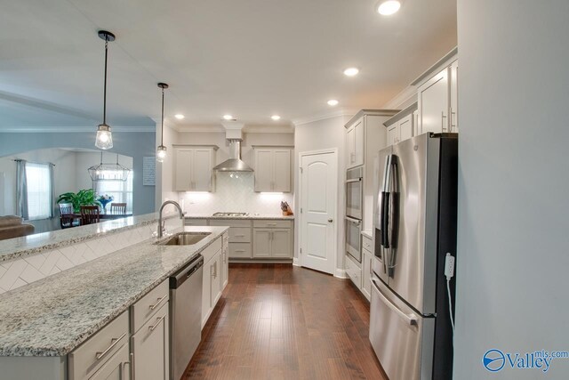 kitchen with decorative light fixtures, appliances with stainless steel finishes, sink, dark hardwood / wood-style floors, and wall chimney exhaust hood