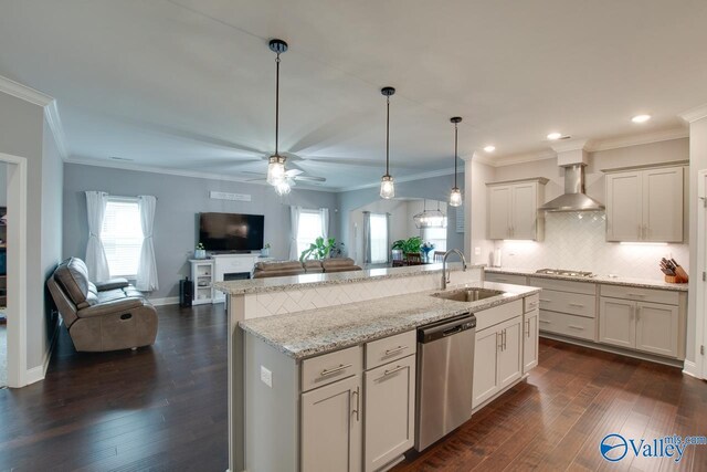 kitchen with appliances with stainless steel finishes, sink, wall chimney exhaust hood, an island with sink, and dark wood-type flooring