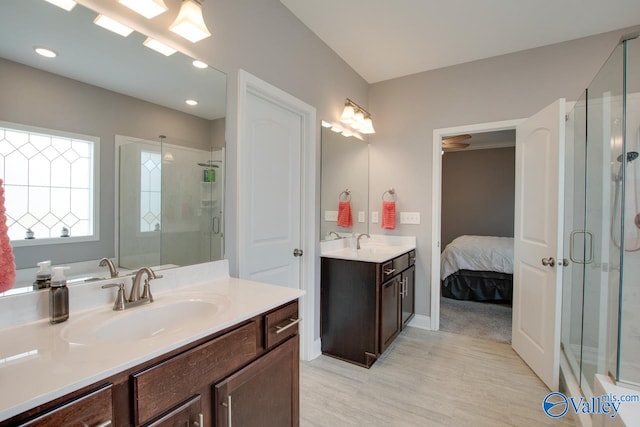 bathroom featuring a shower with door and vanity