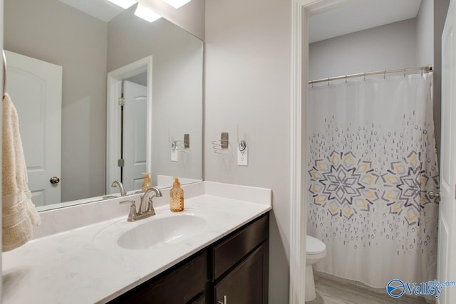 bathroom with vanity, toilet, and hardwood / wood-style floors