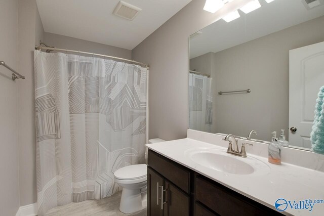 bathroom with walk in shower, toilet, and vanity