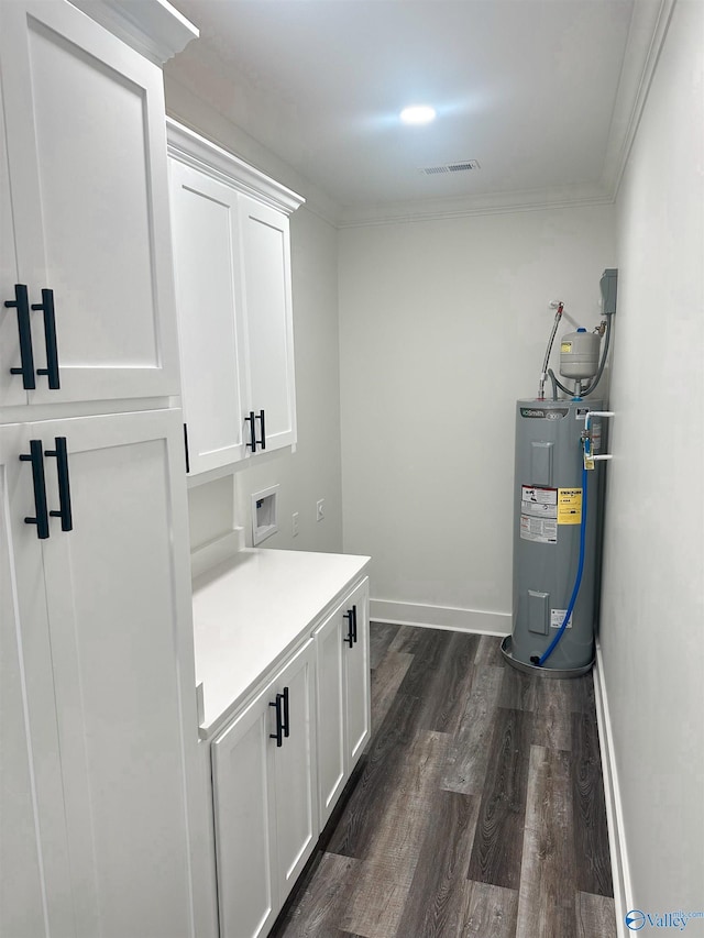 laundry room with electric water heater, dark hardwood / wood-style floors, crown molding, and cabinets