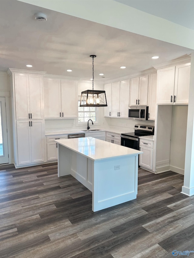 kitchen featuring decorative light fixtures, appliances with stainless steel finishes, white cabinetry, and a kitchen island