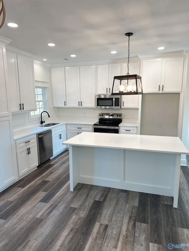 kitchen featuring hanging light fixtures, white cabinets, appliances with stainless steel finishes, and sink