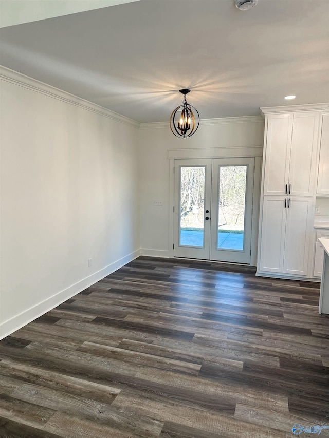 foyer featuring dark wood-type flooring, french doors, crown molding, and a chandelier