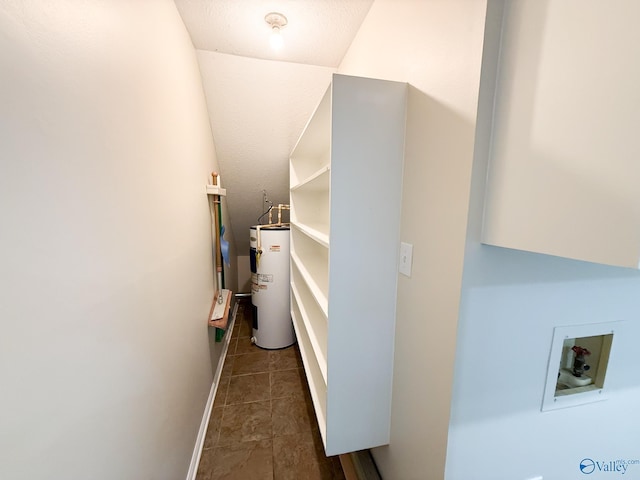 clothes washing area with washer hookup, water heater, dark tile patterned flooring, and baseboards