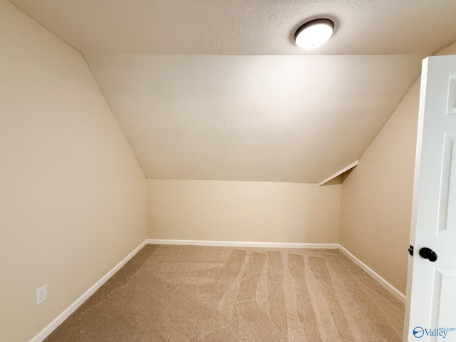 bonus room with baseboards, vaulted ceiling, carpet, and a textured ceiling