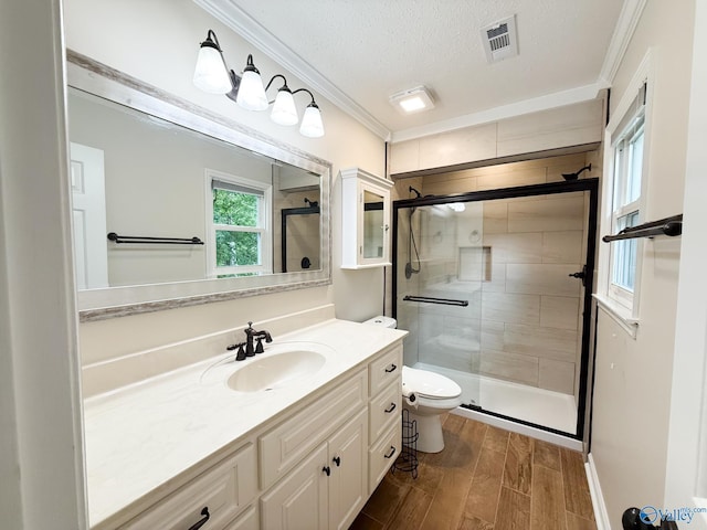 full bathroom featuring a shower stall, wood finished floors, toilet, ornamental molding, and a textured ceiling