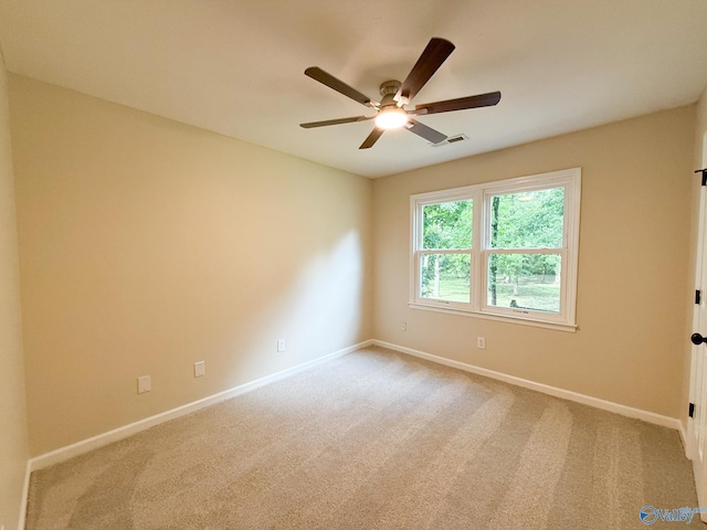 carpeted spare room featuring a ceiling fan and baseboards