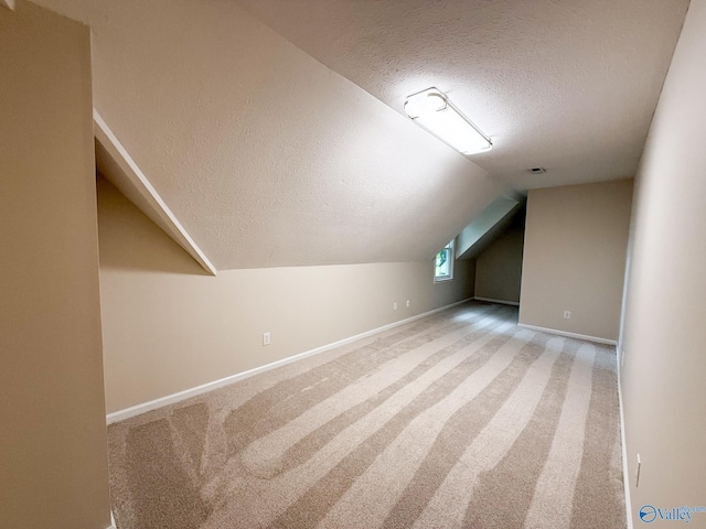 bonus room featuring a textured ceiling, lofted ceiling, baseboards, and carpet flooring