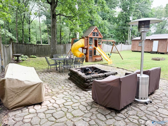 view of patio / terrace with an outdoor fire pit, a playground, outdoor dining area, a shed, and an outdoor structure
