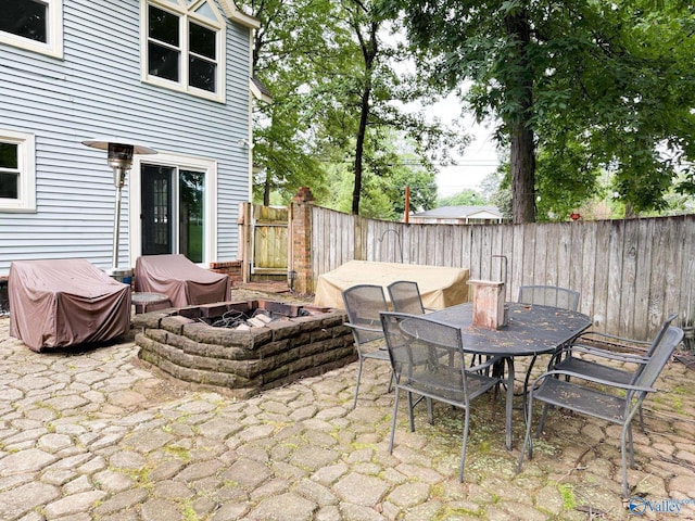 view of patio featuring a fenced backyard, outdoor dining space, and an outdoor fire pit