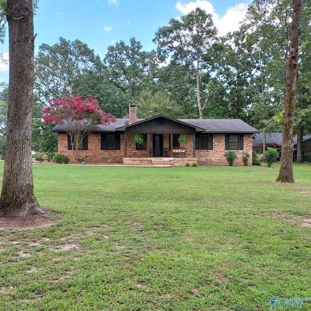 view of front of house featuring a front lawn, crawl space, a chimney, and brick siding