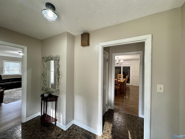 corridor featuring a textured ceiling, visible vents, and baseboards