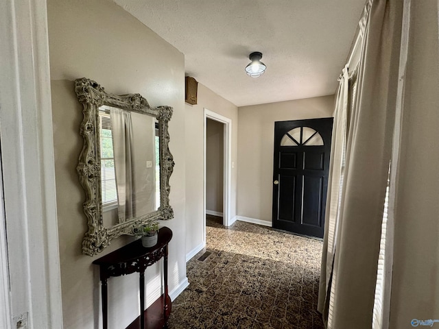 entryway with visible vents, baseboards, and a textured ceiling