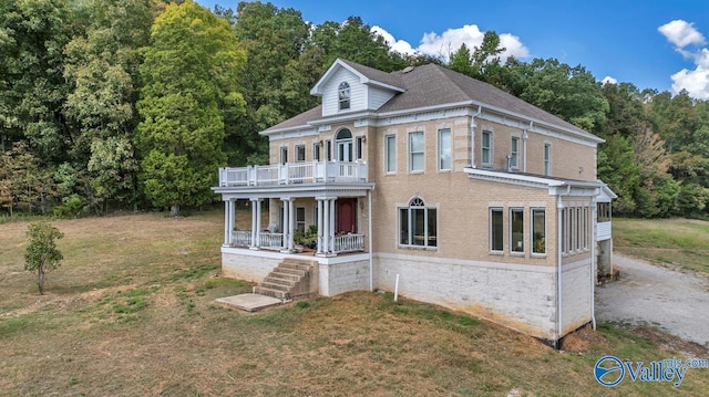 view of front of house with a balcony and a front lawn