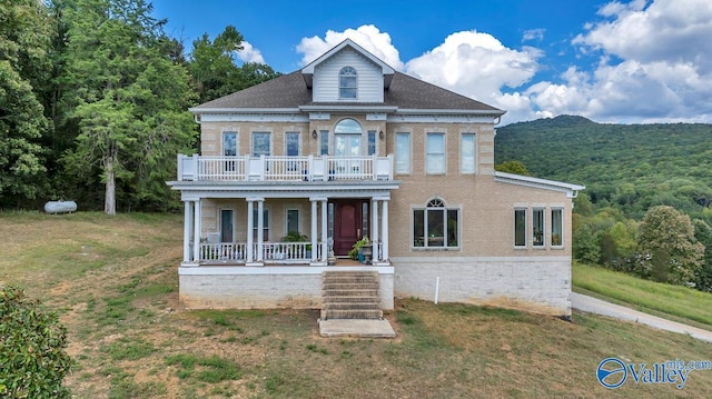 view of front of home featuring a balcony, covered porch, and a front yard