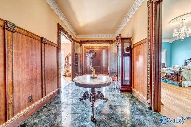 foyer entrance featuring ornamental molding, wood-type flooring, and a chandelier