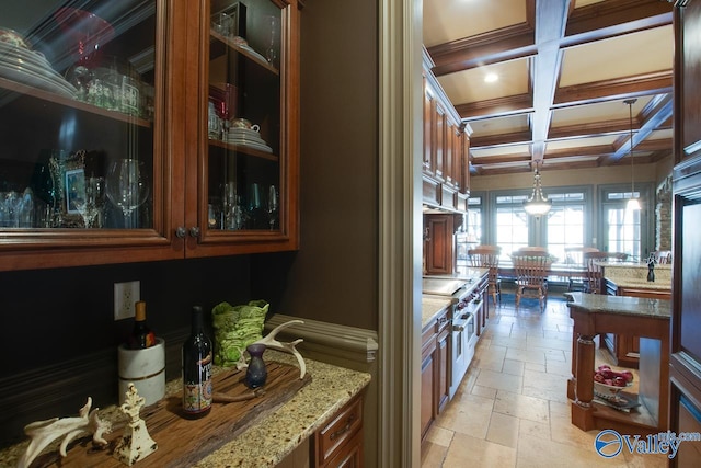 kitchen with decorative light fixtures, beamed ceiling, cooktop, light stone countertops, and coffered ceiling