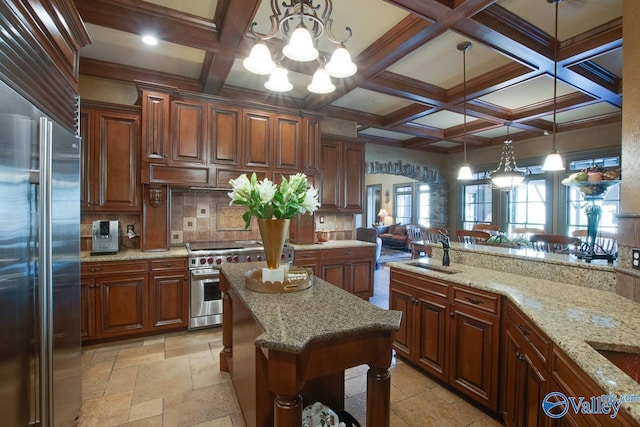 kitchen featuring light stone countertops, hanging light fixtures, premium appliances, a notable chandelier, and sink