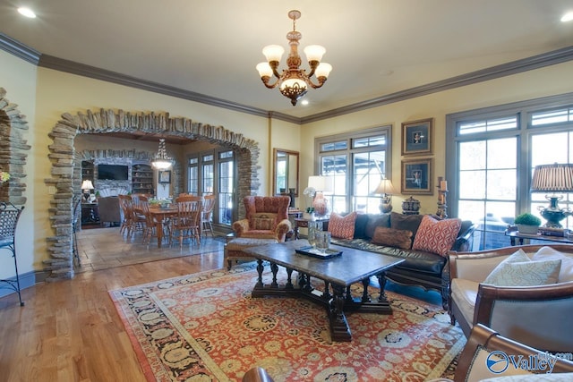 living room with a notable chandelier, light hardwood / wood-style flooring, and ornamental molding