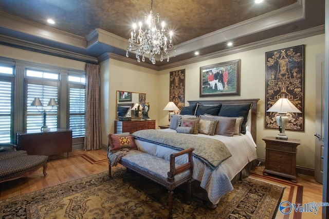 bedroom featuring an inviting chandelier, ornamental molding, a tray ceiling, and hardwood / wood-style floors