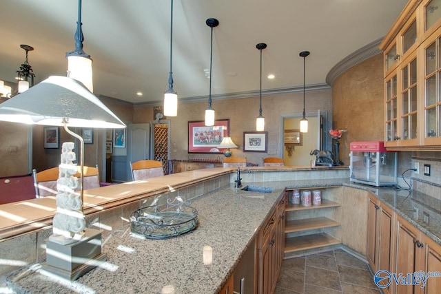 kitchen with sink, pendant lighting, crown molding, and light stone countertops