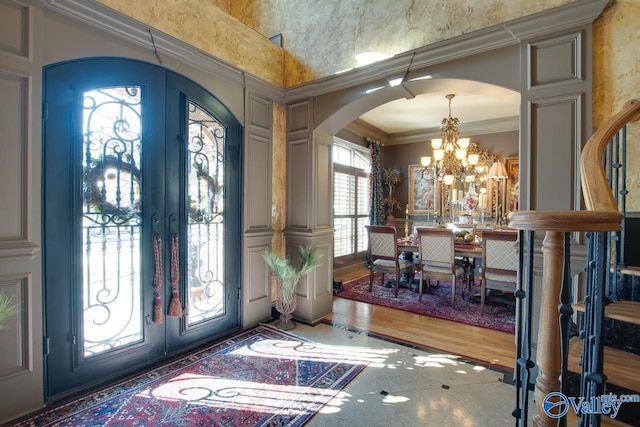 foyer featuring a notable chandelier, french doors, and ornamental molding