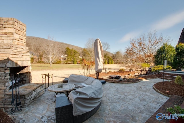 view of patio featuring an outdoor stone fireplace and a mountain view