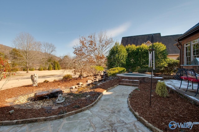 view of yard featuring a patio area, an in ground hot tub, and a mountain view