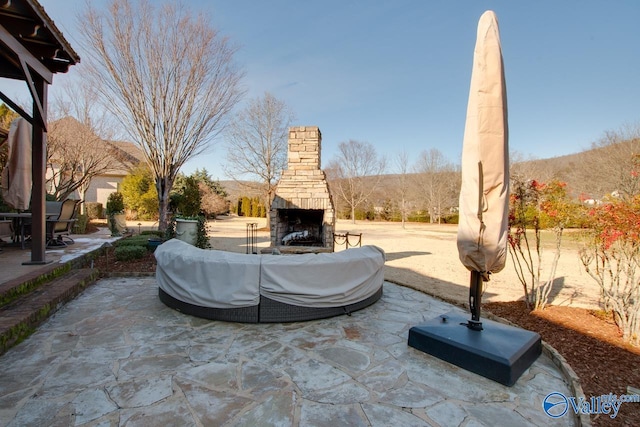 view of patio with a mountain view and an outdoor stone fireplace