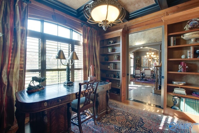 office area with built in shelves, an inviting chandelier, crown molding, and a wealth of natural light