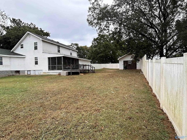 view of yard featuring a sunroom, a fenced backyard, and an outdoor structure