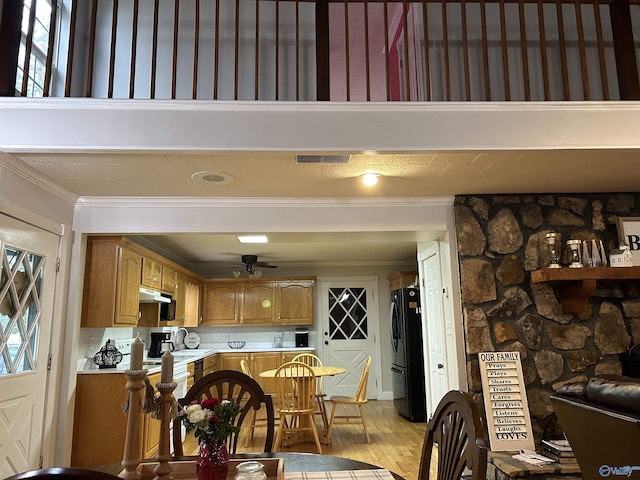 dining area featuring light wood-style floors, visible vents, ceiling fan, and ornamental molding