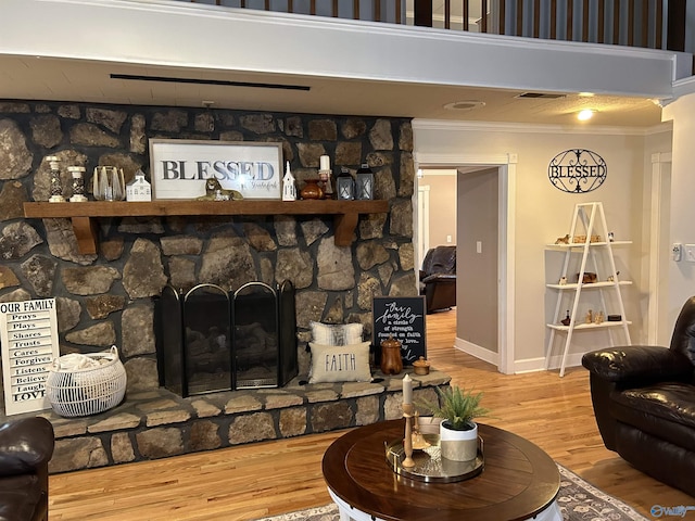 living area with a fireplace, crown molding, baseboards, and wood finished floors