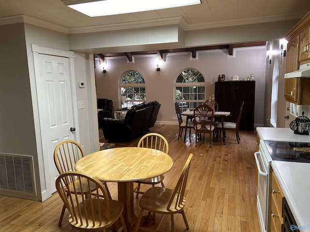 dining room featuring light wood finished floors, baseboards, visible vents, and ornamental molding