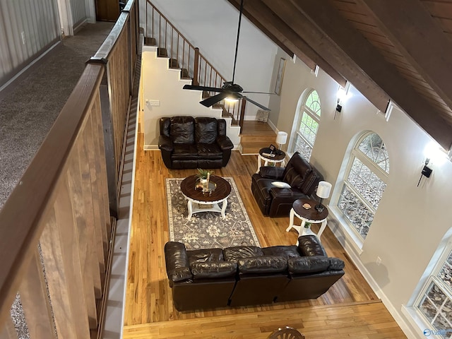 living room featuring high vaulted ceiling, beam ceiling, baseboards, and wood finished floors