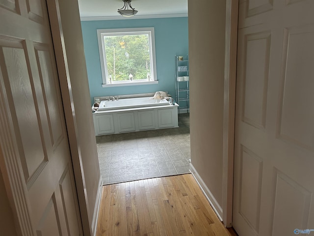 bathroom featuring ornamental molding, wood finished floors, baseboards, and a bath