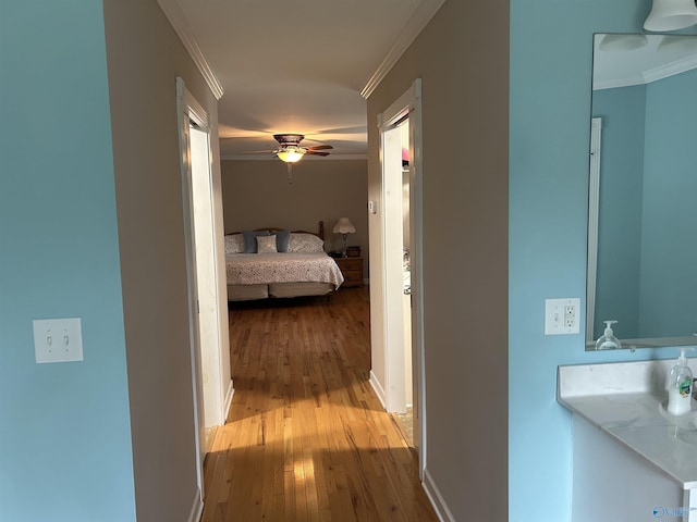 corridor featuring baseboards, wood finished floors, and crown molding