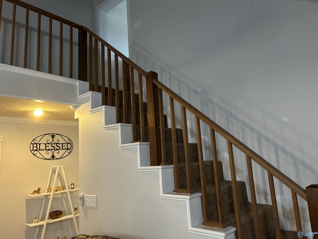 stairs with ornamental molding and a towering ceiling