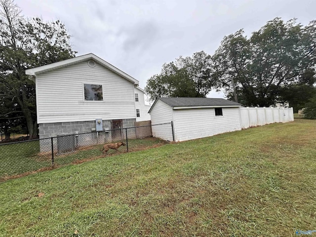 view of home's exterior featuring an outbuilding, a fenced backyard, and a lawn