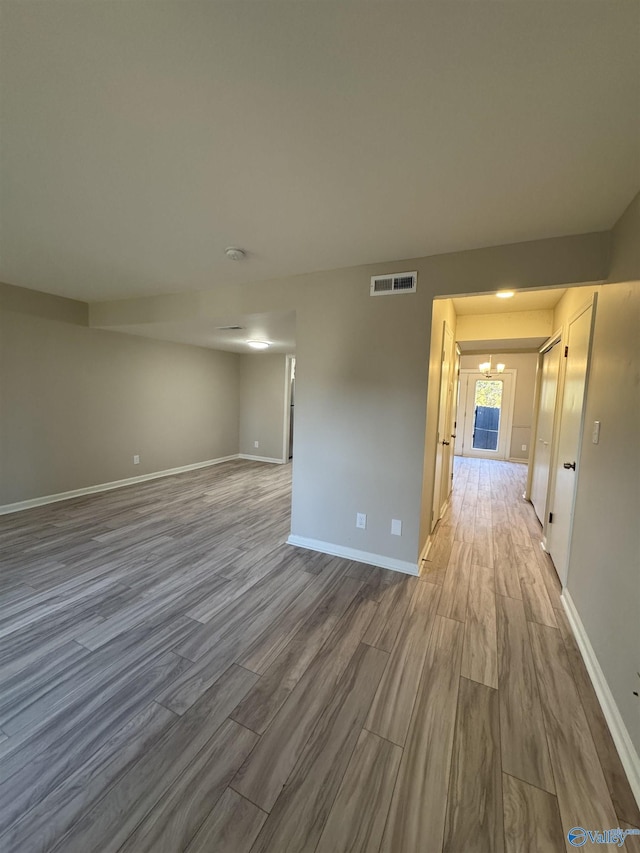 empty room with hardwood / wood-style flooring and a notable chandelier